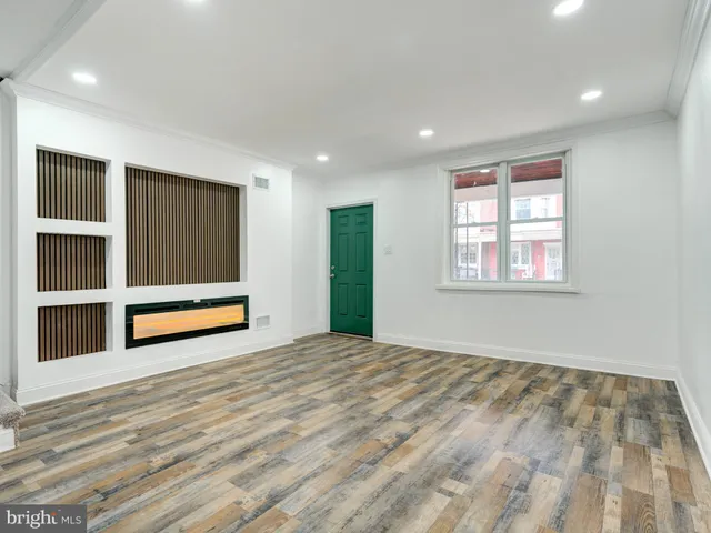a view of an empty room with wooden floor and windows