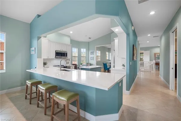 a large dining hall with stainless steel appliances granite countertop a living room and couches with wooden floor