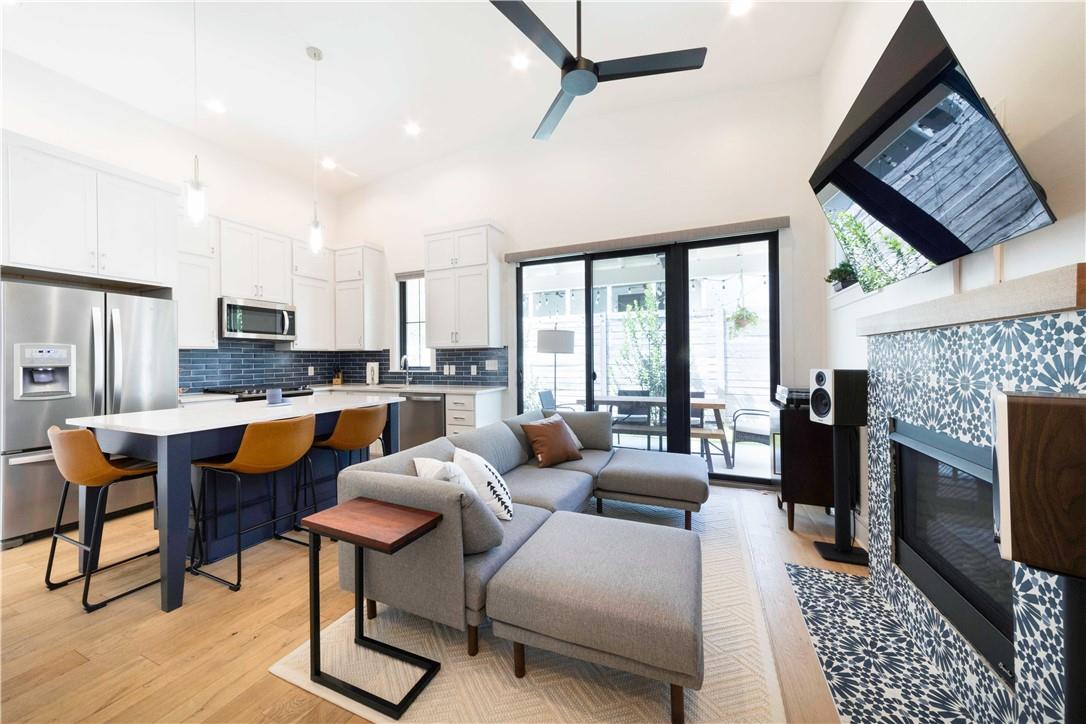 2002 East 9th Street, Unit 2 Austin, TX 78702 - Photo 4 of 32 A striking patterned tile fireplace anchors this bright, open-concept living area with a sleek kitchen and outdoor access.