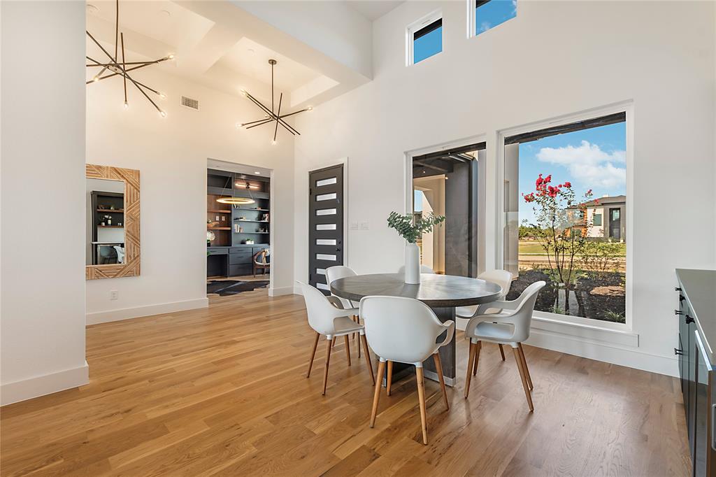 430 Whispering Way Red Oak, TX 75154 - Photo 10 of 40 Expansive dining area featuring high ceilings, wood-finish flooring, two modern linear chandeliers, and large windows with transom lighting