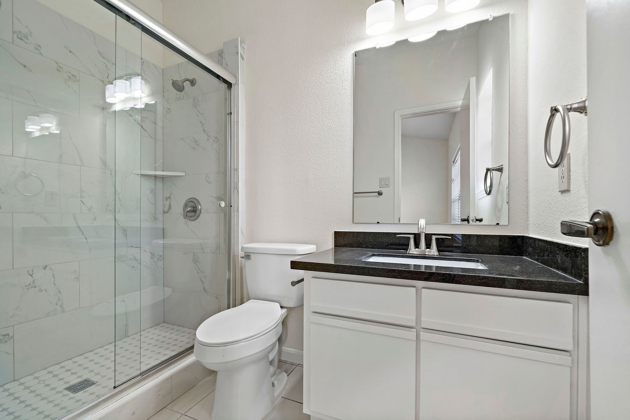 7941 Knight Road, Unit 20 Houston, TX 77054 - Photo 8 of 11 Updated secondary bathroom with granite countertops, modern fixtures, and a sleek glass-enclosed shower.