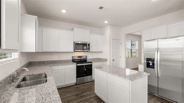 a kitchen with stainless steel appliances granite countertop a refrigerator and a sink