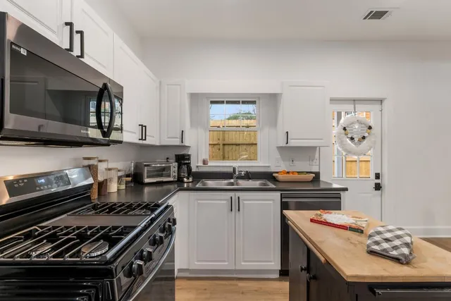 a kitchen with stainless steel appliances a stove a sink dishwasher and cabinets with wooden floor