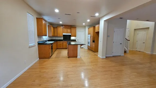 a view of a living room with kitchen island stainless steel appliances wooden floor and view living room