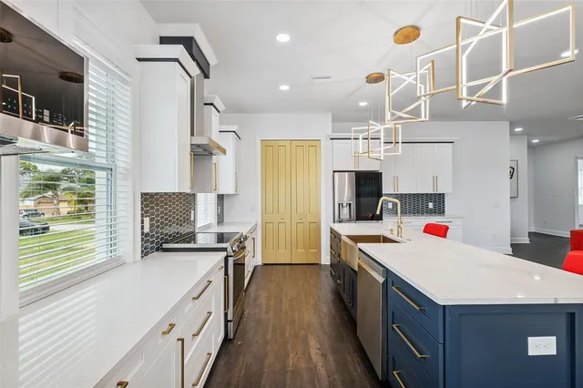 a kitchen with kitchen island granite countertop a stove a sink dishwasher and a refrigerator with wooden floor