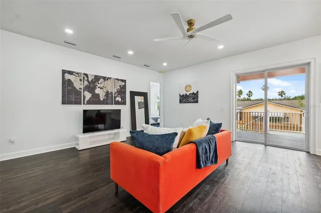 a living room with furniture kitchen view and a wooden floor