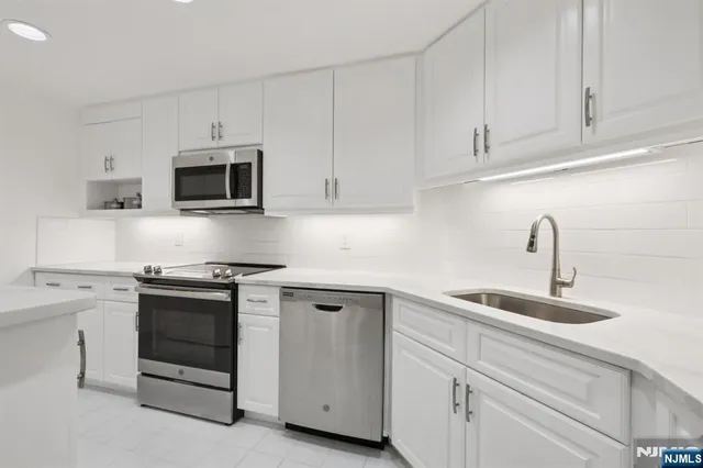 a kitchen with stainless steel appliances granite countertop white cabinets and stove