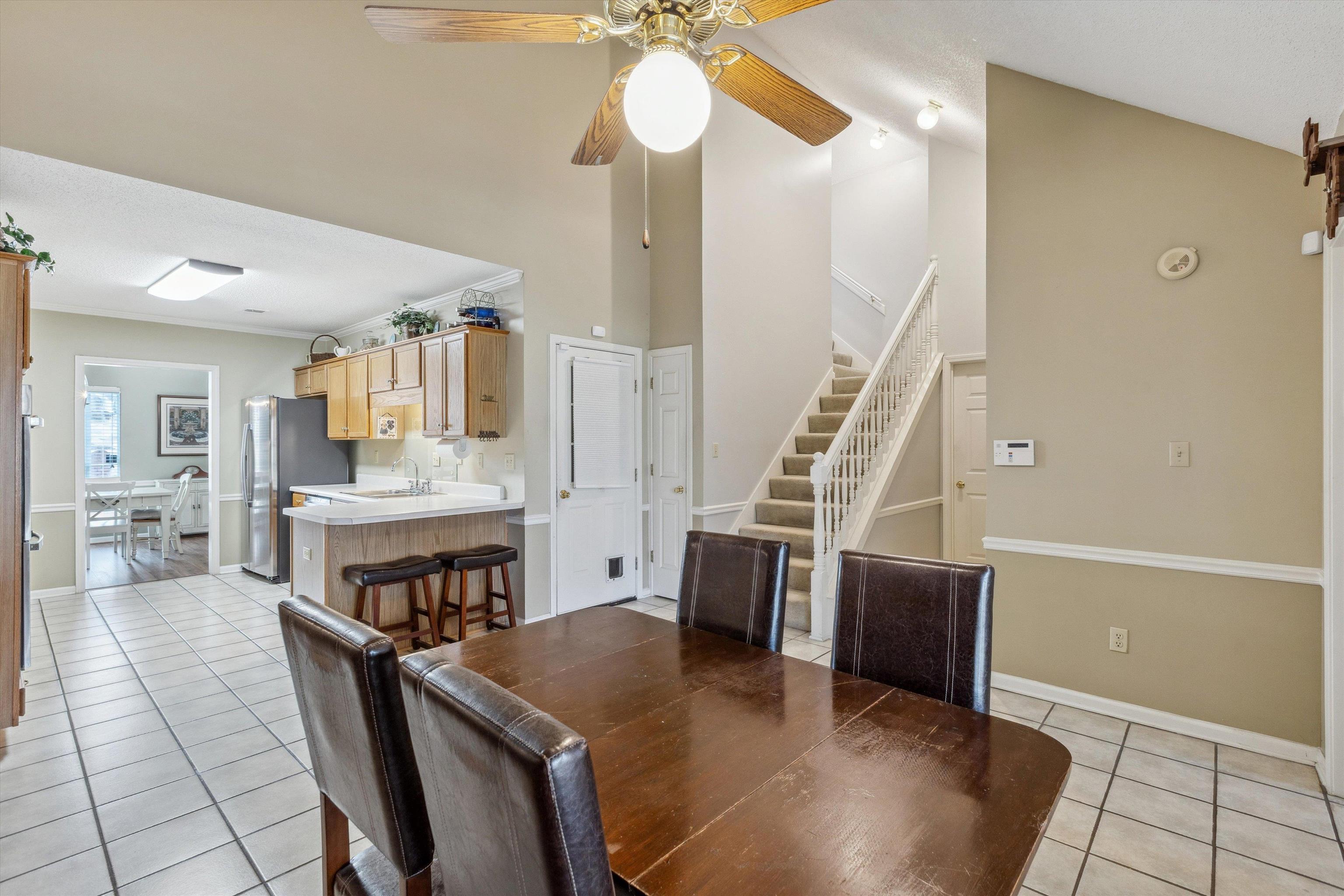 6302 Daybreak Drive Bartlett, TN 38135 - Photo 11 of 22 Dining space with high vaulted ceiling, a ceiling fan, stairway, light tile patterned flooring, and baseboards