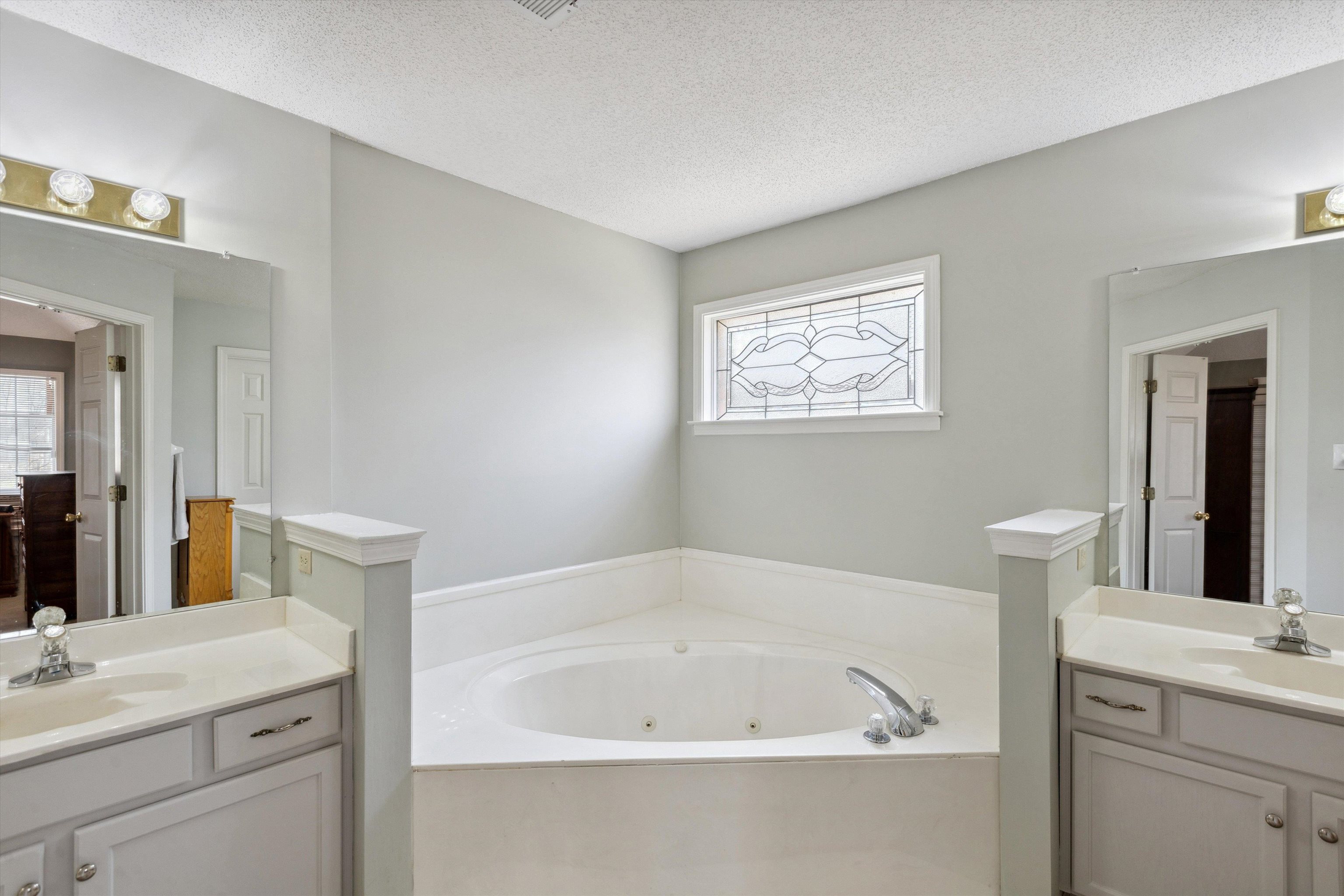 6302 Daybreak Drive Bartlett, TN 38135 - Photo 13 of 22 Bathroom with a textured ceiling, two vanities, a whirlpool tub, and a sink