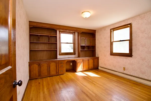 an empty room with wooden floor and windows
