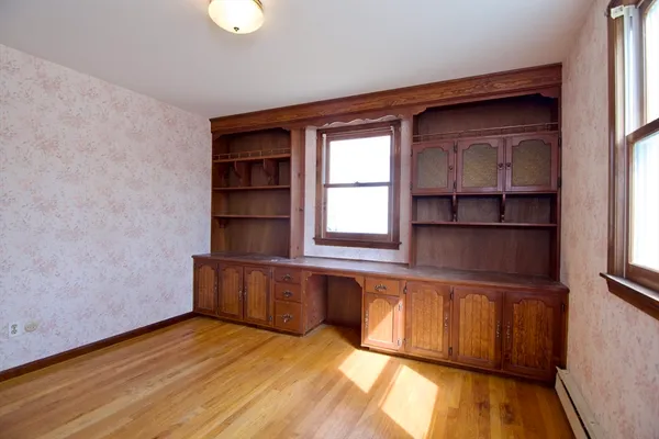 a view of empty room with wooden floor and fan