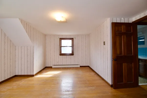 a view of an empty room with closet and a window