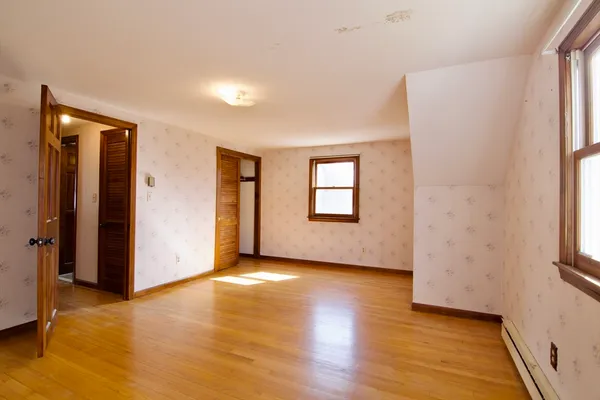 a view of an empty room with wooden floor and a window