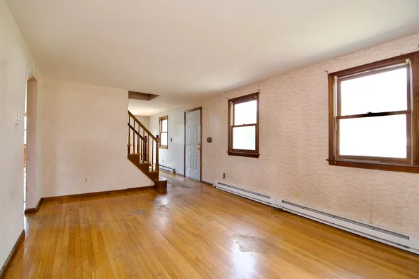 a view of an empty room with wooden floor and a window