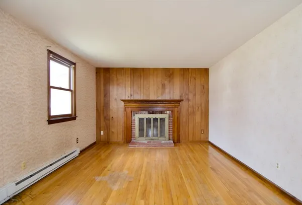 an empty room with wooden floor fireplace and windows