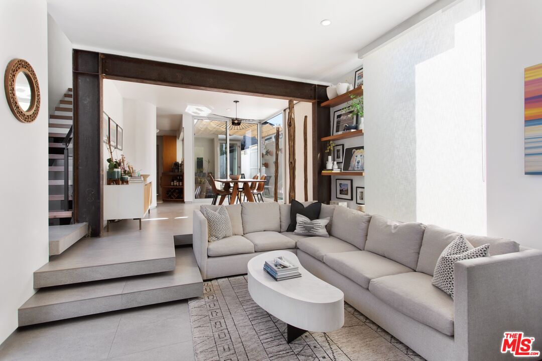 a living room with furniture and a large mirror next to a window