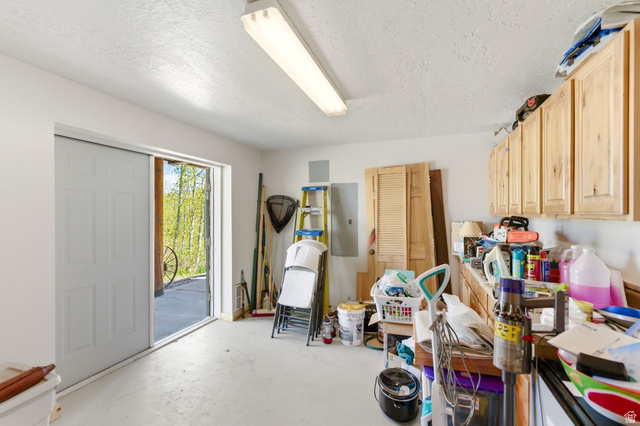2096 South Aspen Ridge Coalville, UT 84017 - Photo 30 of 44 Utility room featuring painted concrete flooring, overhead fluorescent lighting, a sliding white panel door, and light wood cabinetry with upper storage