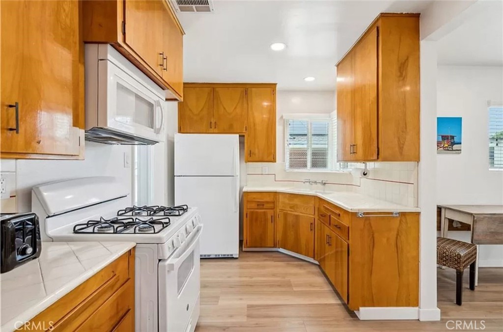 5340 East Mezzanine Way Long Beach, CA 90808 - Photo 9 of 18 a kitchen with stainless steel appliances granite countertop a stove a sink dishwasher and a refrigerator with wooden floor