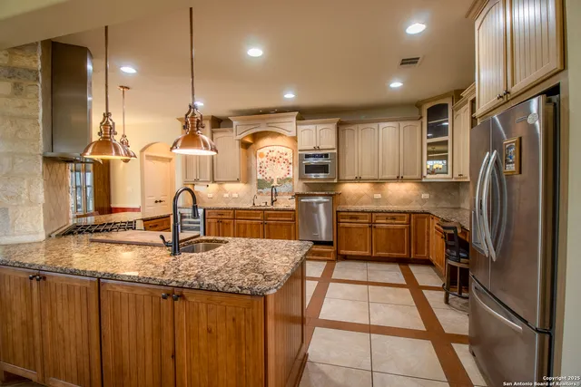 a kitchen with stainless steel appliances granite countertop a sink a stove and a refrigerator