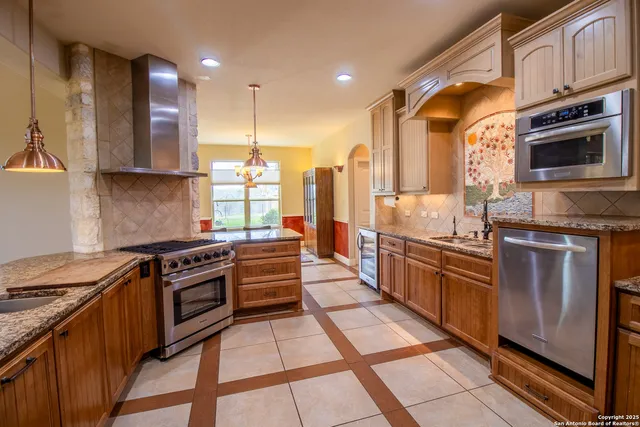 a large kitchen with stainless steel appliances granite countertop a stove a sink and a microwave