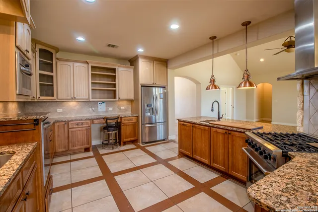 a kitchen with stainless steel appliances granite countertop a stove a sink and a refrigerator