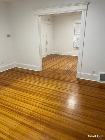 a view of empty room with wooden floor