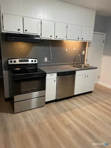 a kitchen with granite countertop a stove top oven and cabinets