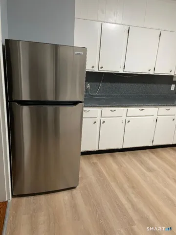 a view of a refrigerator in kitchen and white cabinets