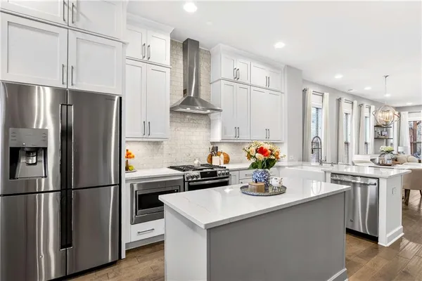 a kitchen with stainless steel appliances a refrigerator a sink a stove and white cabinets