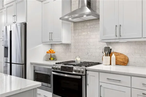 a kitchen with stainless steel appliances granite countertop a stove a refrigerator and a white cabinets