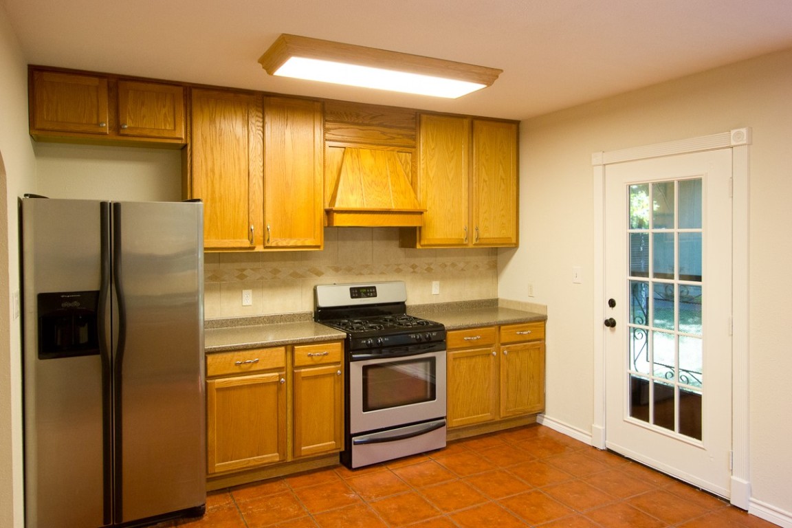 5901 South 1st Street Austin, TX 78745 - Photo 5 of 19 a kitchen with stainless steel appliances granite countertop a stove a refrigerator and a sink