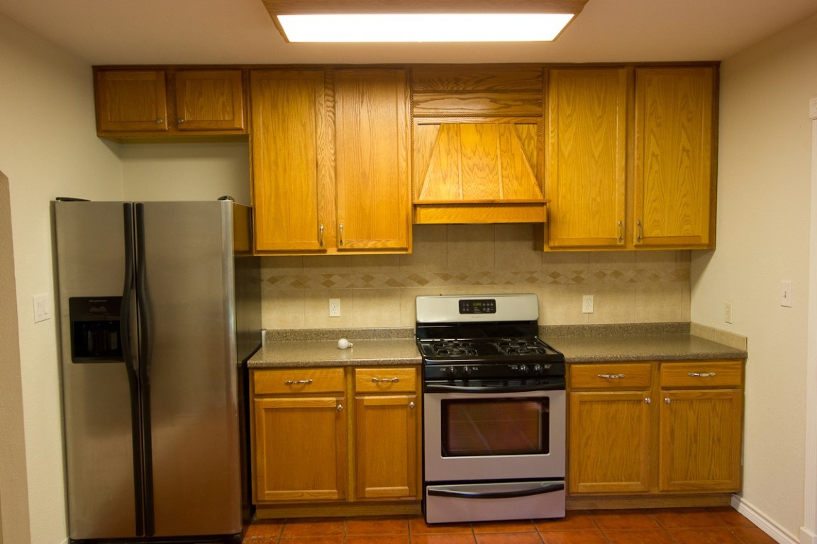 5901 South 1st Street Austin, TX 78745 - Photo 7 of 19 a kitchen with stainless steel appliances wooden cabinets and a stove top oven