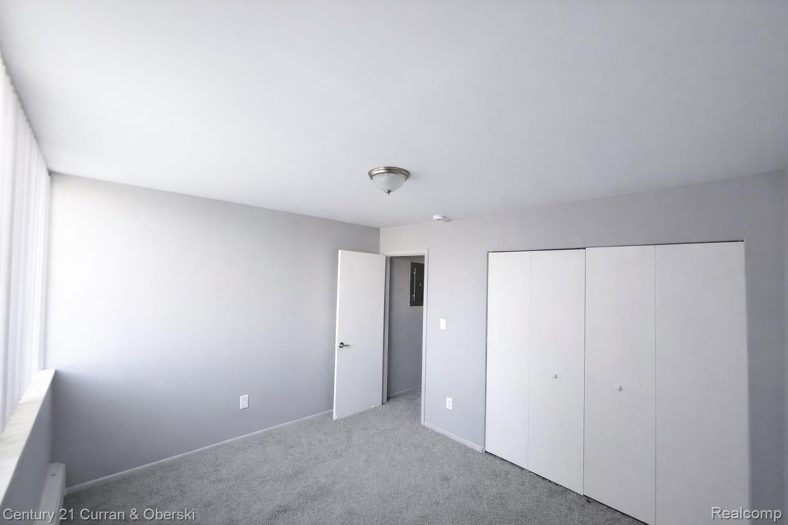 6035 Southfield Road, Unit 12 Detroit, MI 48228 - Photo 8 of 10 Unfurnished bedroom with light colored carpet, a closet, and a baseboard radiator