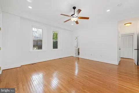 a view of empty room with wooden floor and fan