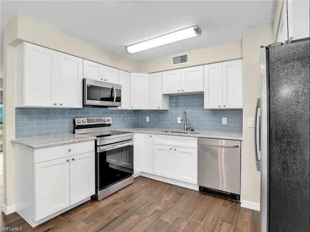a kitchen with stainless steel appliances granite countertop a stove top oven a sink and cabinets
