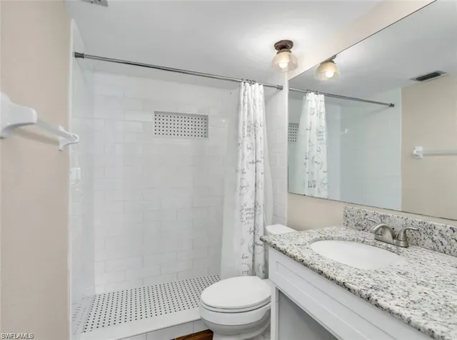 a bathroom with a granite countertop sink toilet and shower