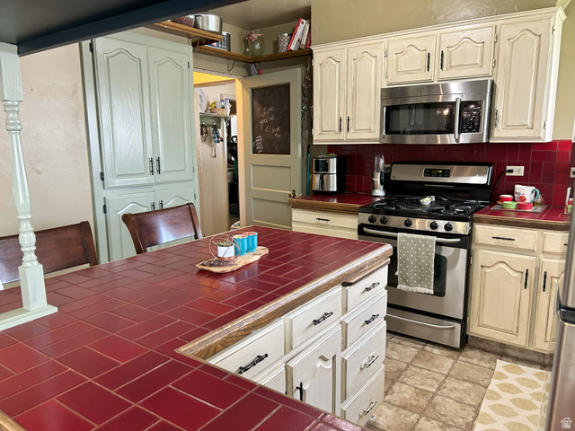 40 South State Street Scipio, UT 84656 - Photo 12 of 39 Kitchen featuring tile countertops, stainless steel appliances, backsplash, and light stone finish flooring
