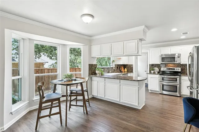 a kitchen with white cabinets stainless steel appliances and dining table