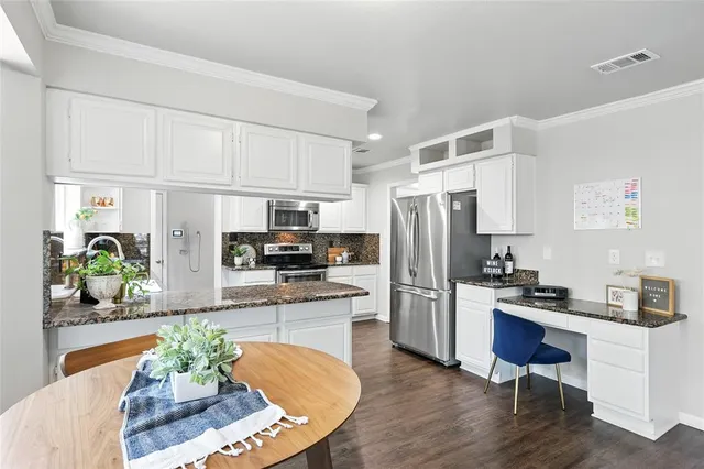 a kitchen with stainless steel appliances granite countertop a refrigerator a stove a sink dishwasher and white cabinets with wooden floor