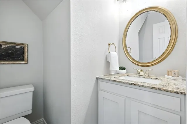 a bathroom with a granite countertop toilet a sink and a mirror