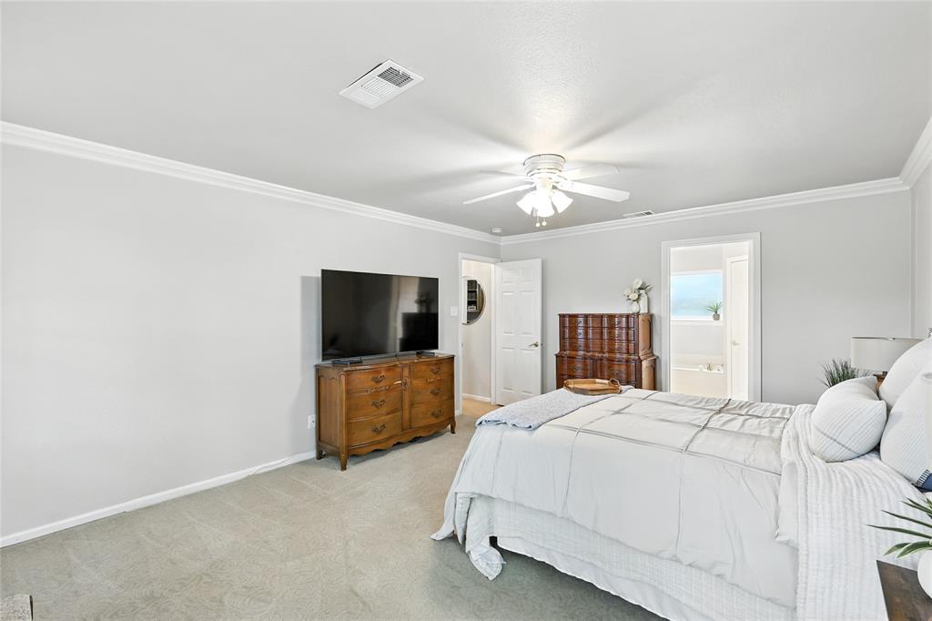 1330 Laredo Court Denton, TX 76205 - Photo 23 of 40 a spacious bedroom with a bed and a flat screen tv
