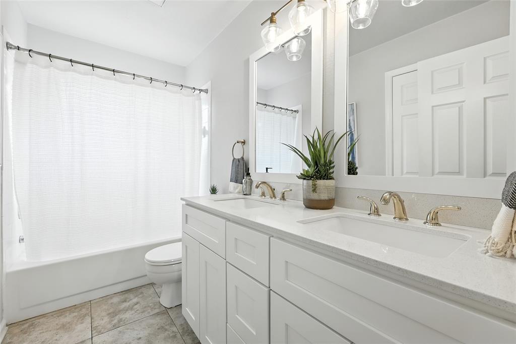 1330 Laredo Court Denton, TX 76205 - Photo 28 of 40 a bathroom with a granite countertop sink a toilet and a shower