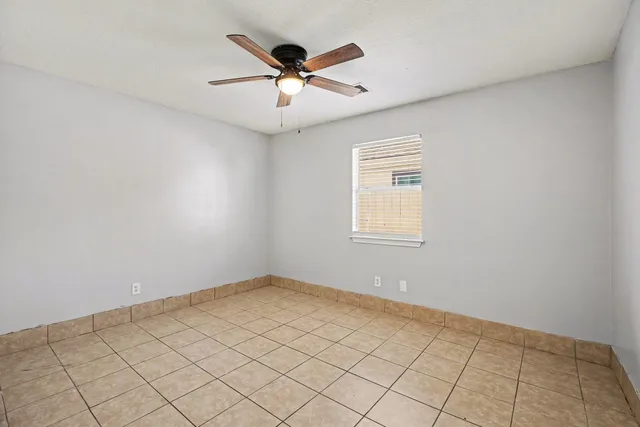 an empty room with ceiling fan and windows
