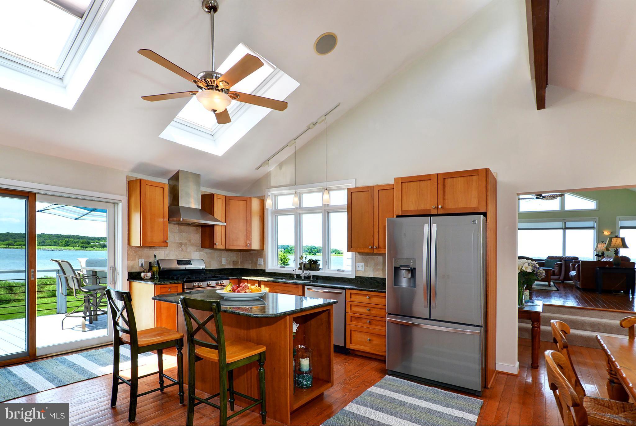 401 Old Point Road Chester, MD 21619 - Photo 13 of 28 a kitchen with stainless steel appliances granite countertop a refrigerator a stove a sink a dining table and chairs with wooden floor