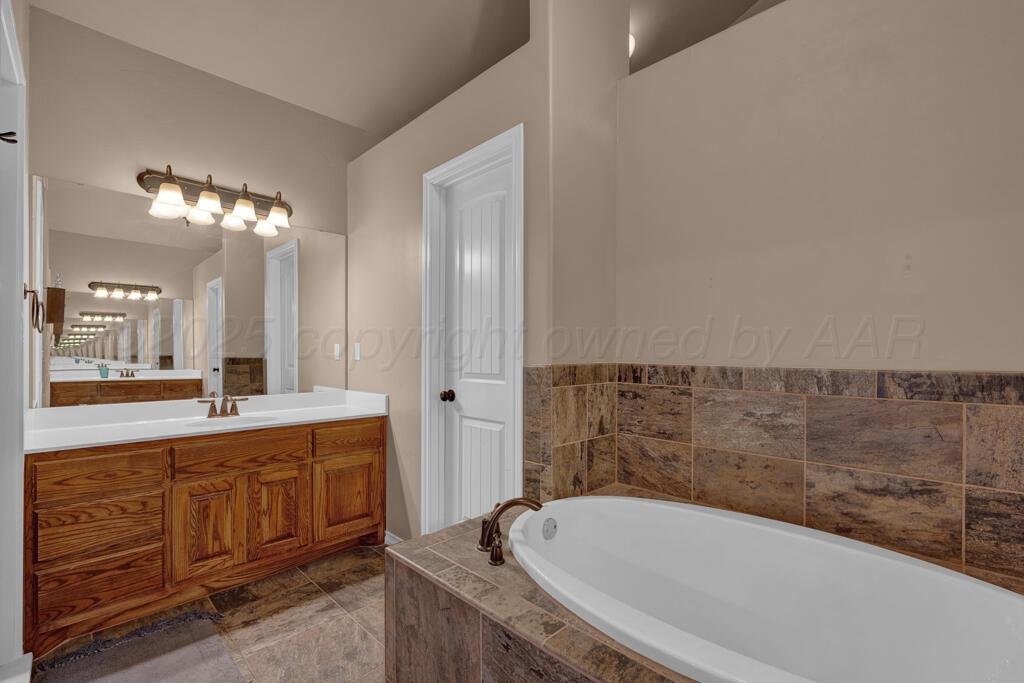 17801 Stone Creek Road Amarillo, TX 79124 - Photo 14 of 31 a bathroom with a granite countertop tub sink and mirror