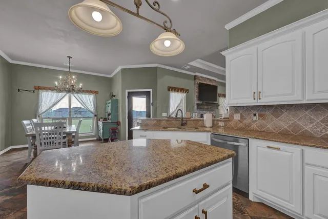 a kitchen with kitchen island granite countertop a sink and dishwasher a white cabinets with wooden floor