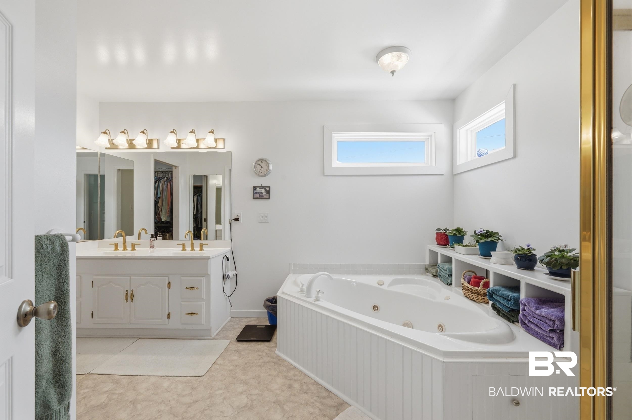 15855 Calvin Richerson Road Bay Minette, AL 36507 - Photo 57 of 83 Bathroom featuring a jetted corner tub, dual-sink vanity with gold-tone fixtures, and white cabinetry