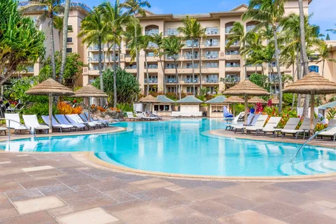 a view of a swimming pool with lawn chairs under an umbrella
