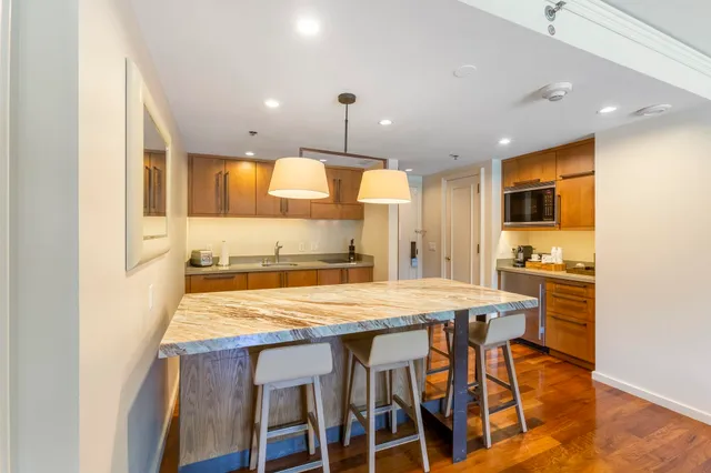 a kitchen with stainless steel appliances granite countertop a table chairs sink and cabinets