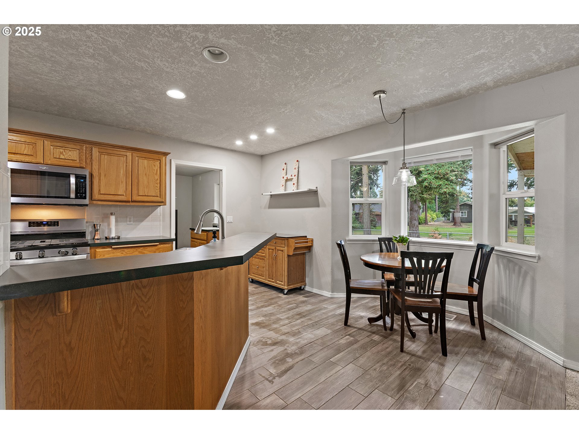 7771 St Charles Street Northeast Keizer, OR 97303 - Photo 14 of 42 a open kitchen with stainless steel appliances granite countertop a stove top oven a sink a dining table and chairs